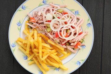 a plate of fresh sausage salad and french fries 
