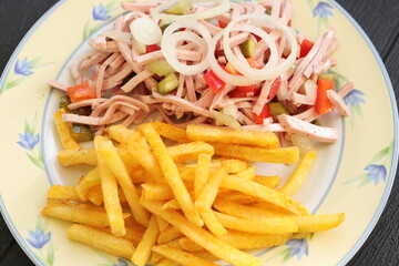 a plate of fresh sausage salad and french fries 