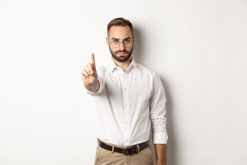 Serious man in glasses showing stop sign, shaking finger to prohibit and forbid, standing over...