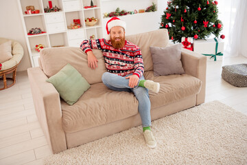 Full length body size photo bearded man chilling at home sitting on sofa near decorated xmas tree