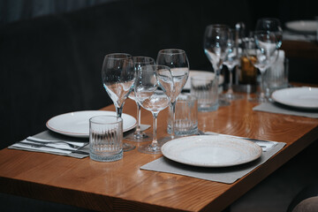 Beautiful table set in elegant restaurant with glass of wine, glass of water, knife, spoon and fork, cutlery, ready to welcome customers.
