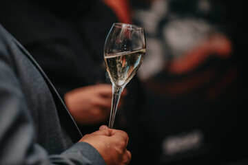 Elegant waiter pours champagne from bottle into glass at restaurant. Sommelier tasting white sparkling wine in restaurant. Copy space for text menu elegant or recipe on dark background.