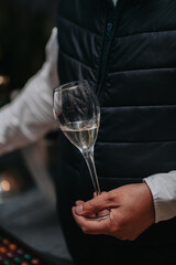Elegant waiter pours champagne from bottle into glass at restaurant. Sommelier tasting white sparkling wine in restaurant. Copy space for text menu elegant or recipe on dark background.