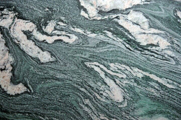 Full frame close-up view of a green and white marbled granite stone surface with a variety of patterns