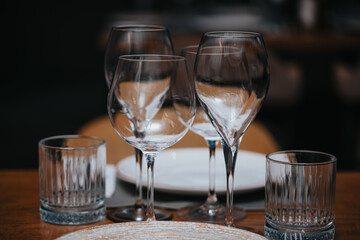 Beautiful table set in elegant restaurant with glass of wine, glass of water, knife, spoon and fork, cutlery, ready to welcome customers.