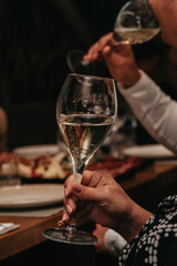 Elegant waiter pours champagne from bottle into glass at restaurant. Sommelier tasting white sparkling wine in restaurant. Copy space for text menu elegant or recipe on dark background.