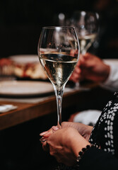 Elegant waiter pours champagne from bottle into glass at restaurant. Sommelier tasting white sparkling wine in restaurant. Copy space for text menu elegant or recipe on dark background.