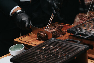 Cooking juicy beef steak by chef hands with copy space for text menu elegant or recipe on dark background.