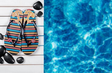 Colored flip flops sitting on the edge of a swimming pool.