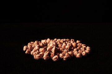 Photograph of a batch of chickpeas on a black background. Close-up image. Dark food