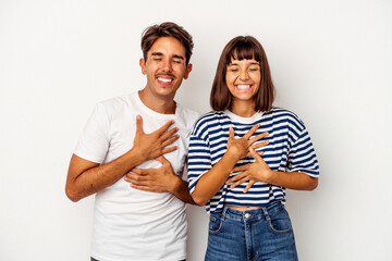 Fototapeta premium Young mixed race couple isolated on white background laughs happily and has fun keeping hands on stomach.