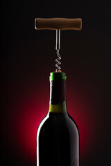 Wine bottle and wine opener on black background with red backlight