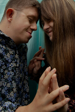 Portrait of young couple with Down Syndrome and Foetal Alcohol Syndrome touching hands in front of blue background