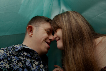 Portrait of young couple with Down Syndrome and Foetal Alcohol Syndrome touching noses in front of...