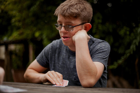 Young man with Foetal Alcohol Syndrome playing cards outdoors looking confident