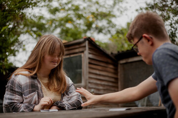 Young couple with Down Syndrome and Foetal Alcohol Syndrome playing cards outdoors