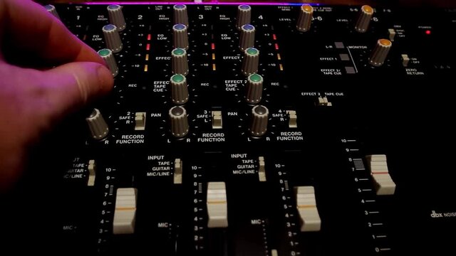 Front view of portative cassette tape studio mixer closeup shot with hands adjusting knobs