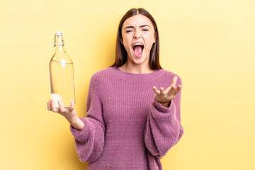 young hispanic woman looking angry, annoyed and frustrated. water bottle concept