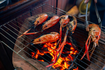 Big fresh prawns laying on the grill, being burned to turn orange, are a very tasty part of Thai food.