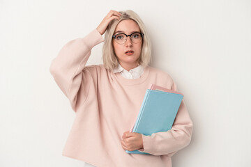 Young caucasian student woman holding books isolated on white background being shocked, she has...