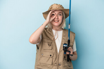 Young caucasian fisherwoman holding a rod isolated on blue background excited keeping ok gesture on eye.