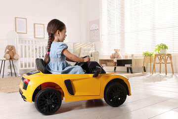 Adorable child driving toy car in room at home