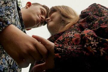 Low angle portrait of young couple with Down Syndrome and Foetal Alcohol Syndrome holding hands and...