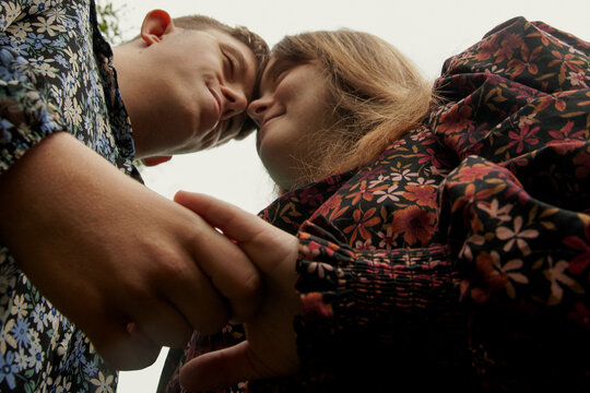 Low angle portrait of young couple with Down Syndrome and Foetal Alcohol Syndrome holding hands and heads touching