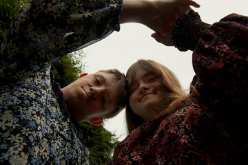 Low angle portrait of young couple with Down Syndrome and Foetal Alcohol Syndrome holding hands and...