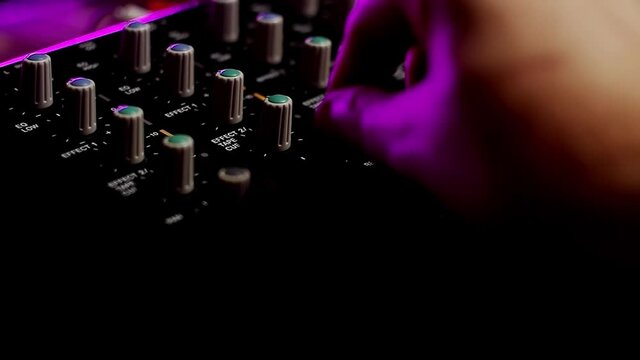 Portative cassette tape studio mixer closeup shot with hand adjusting knobs