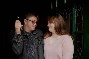 Young couple with Down Syndrome and Foetal Alcohol Syndrome standing at front door with key and and...
