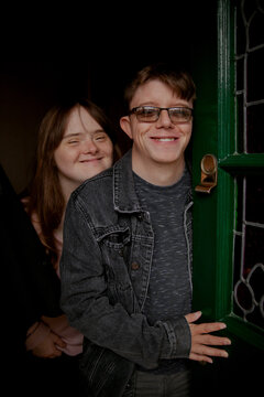 Young couple with Down Syndrome and Foetal Alcohol Syndrome standing at front door and smiling