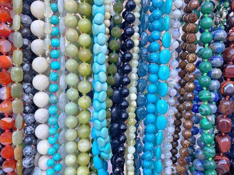Colorful beads background. Beads made natural gems  turquoise, malachite, mother pearl, jade, quartz, agate, lapis lazuli, jasper, cacholong, tiger's eye stone, topaz, fluorite. Beautiful bijouterie.