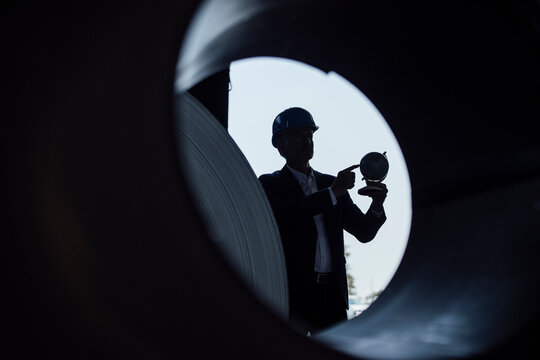 Businessman holding globe while standing in steel mill