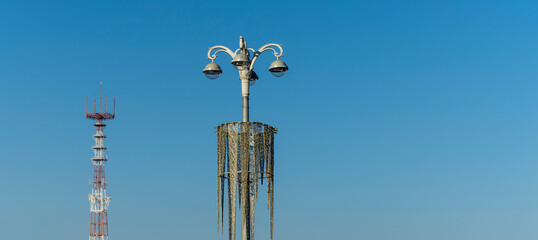 Lamp post and tv tower against blue sky. Space for text. Technology concept.