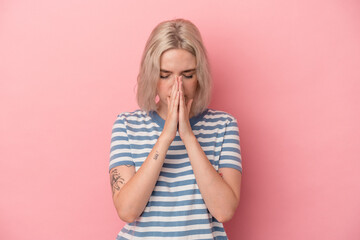 Young caucasian woman isolated on pink background praying, showing devotion, religious person looking for divine inspiration.