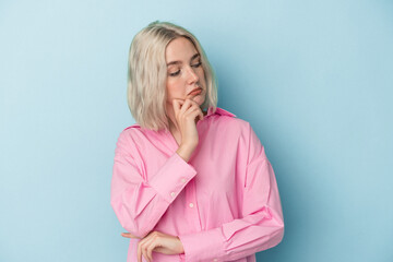 Young caucasian woman isolated on blue background looking sideways with doubtful and skeptical expression.