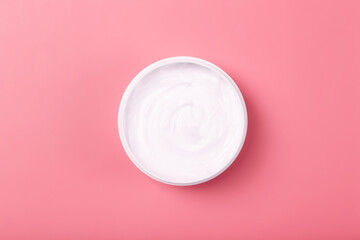 Cosmetic cream background. White cosmetic cream for skin and body in an open white jar on a pink empty background.