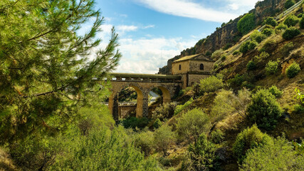 Fototapeta premium Arched bridge and mountain house in green wooded landscape.