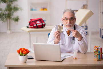 Old male doctor pharmacist working in the clinic