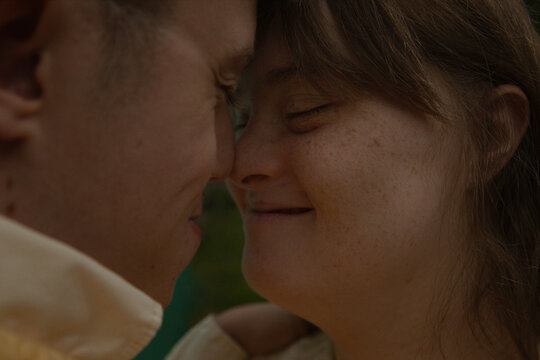 Face to face portrait of young couple with Down Syndrome and Foetal Alcohol Syndrome smiling and touching noses