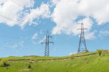 supports of a high-voltage power transmission line in mountainous rough terrain. Delivery of electricity to consumers in remote villages