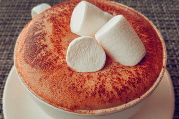 white cup of cappuccino with marshmallows wooden table