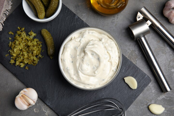 Tasty tartar sauce and ingredients on grey table, flat lay