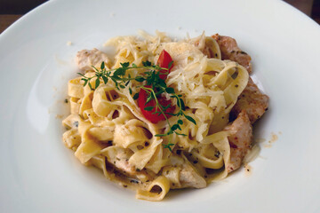 Spaghetti with pieces of meat on a white plate for lunch.