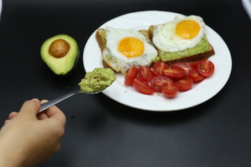 hand holding tomato cherrie, Vegetarian toast with egg and avocado, toast bread, black background