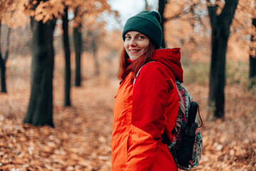 Back view Attractive caucasian smile woman hiking trip backpack in autumn forest, extreme lifestyle, freedom concept.