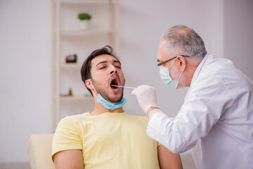 Fototapeta premium Young male patient visiting old male doctor otorhinolaryngologis