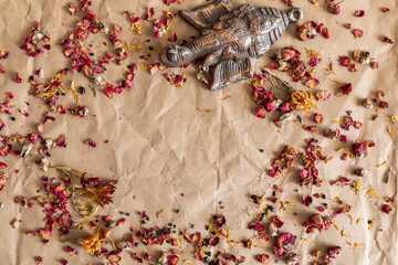 Kraft background with dried roses, nd a decoration of the god Ganesh. Blank space in the centre for text.