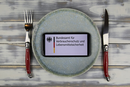 Viersen, Germany - June 9. 2021: Closeup of smartphone with logo lettering of german Bundesamt fur Verbraucherschutz und Lebensmittelsicherheit on plate with cutlery (focus on center)